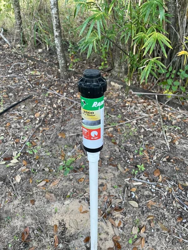 Sprinkler head raised on a riser in a planting bed