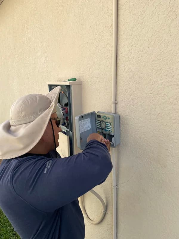 Technician programming a wall-mounted sprinkler controller