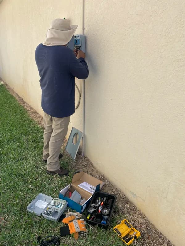 Technician working on a wall-mounted controller with tools on the ground