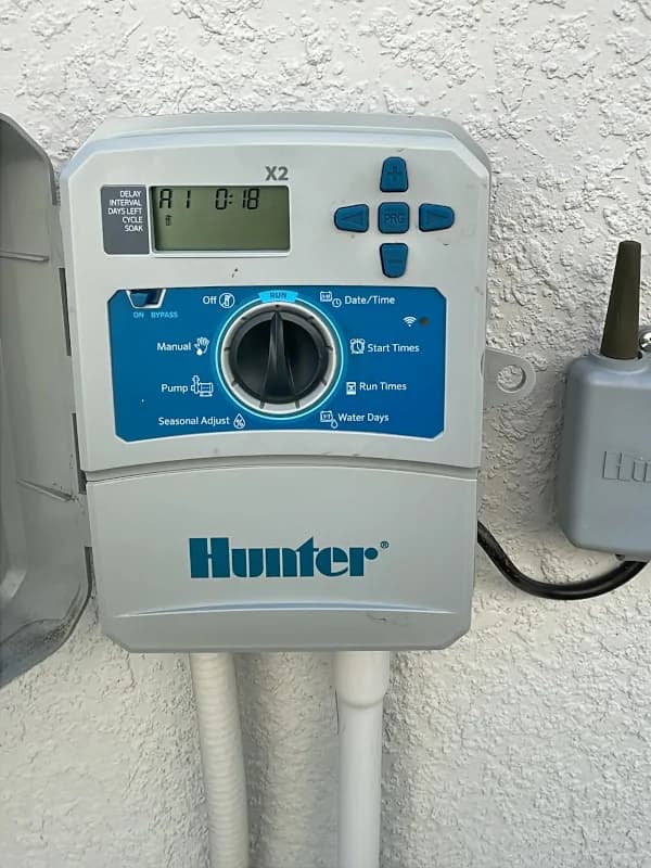 Newly installed Hunter sprinkler controller on an exterior wall