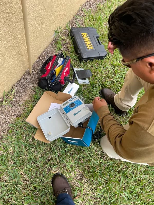 Technician unboxing a new sprinkler controller on the lawn