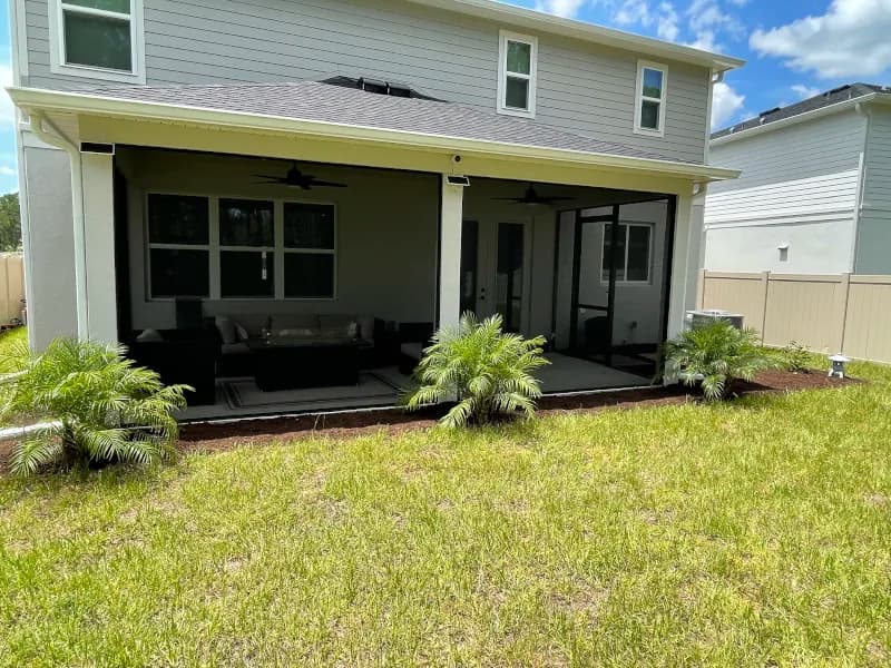 Backyard bed with new tropical plants along a screened lanai